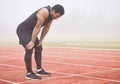 That didnt go according to plan. Full length shot of a handsome young male athlete hunched over on the track after a Royalty Free Stock Photo