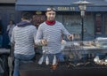 DIEPPE, FRANCE - NOVEMBER 17, 2018: Man cooks herring on the grill. Fair Herring and scallop shell on the market