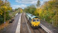 Diesel electric train pulling into Warminster Railway Station against brilliant autumn tree colours in Warminster, Wiltshire, UK