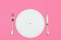 Diet, anorexia and food crisis concept. one pea on an empty white plate Royalty Free Stock Photo