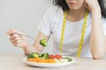 Diet in bored. Closeup broccoli unhappy beautiful asian young woman, girl on dieting, hand holding fork in salad plate, dislike or Royalty Free Stock Photo