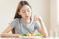 Diet in bored face, unhappy beautiful asian young woman, girl on dieting, holding fork in salad plate, dislike or tired with eat Royalty Free Stock Photo