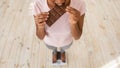 Diet breakdown and unhealthy nutrition. Above view of African American woman eating chocolate bar on scales, closeup
