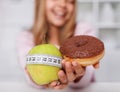 Diet choices concept with apple and doughnut in hands of smiling girl Royalty Free Stock Photo