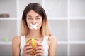 Diet. Close up face of young beautiful sad latin woman with mouth sealed on stick tape