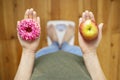 Diet concept. Dieting young woman measuring body weighing on weight scale, hold sweet donut and red apple, making choice between Royalty Free Stock Photo