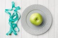 Diet concept. Green Apple on a plate and tape centimeter on a white table Royalty Free Stock Photo