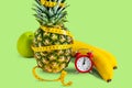 Diet concept  healthy food  vitamins  fitness diet  food concept. Pineapple  apple  nuts with alarm clock on a plate on a green Royalty Free Stock Photo