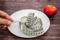 Diet concept. Measuring tape in a white plate on a wooden table and an apple. Royalty Free Stock Photo