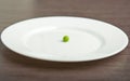 Diet concept. one pea on an empty white plate Royalty Free Stock Photo