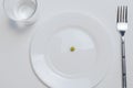 Diet concept. one pea on an empty white plate with fork Royalty Free Stock Photo