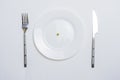 Diet concept. pea on an empty white plate with knife and fork Royalty Free Stock Photo