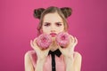 Diet concept. Sad unhappy woman with donuts on vivid colorful pink background