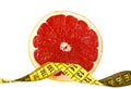 Diet concept: slice of grapefruit and measuring tape on white background