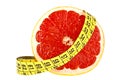 Diet concept: slice of grapefruit and measuring tape on white background