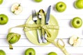 Diet concept table setting with cutlery, yellow measuring tape and green apples on white wooden table.