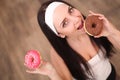 Diet Concept. Young Woman Measuring Body Weight On Weighing Scale While Holding Glazed Donut With Sprinkles. Sweets Are Unhealthy Royalty Free Stock Photo