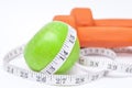 Diet diabetes weight loss concept with tape measure organic green apple and yellow dumbbels on a white background Royalty Free Stock Photo