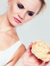 Undecided woman holds cake sweet bun in hand