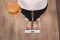 Diet And Fast Food Concept. Overweight Woman Standing On Weighing Scale Holding Burger Hamburger . Unhealthy Junk Food. Dieting Royalty Free Stock Photo