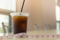 Diet and food concept. Close up of takeaway plastic cup of iced black coffee Americano with measure tape on table in restaurant
