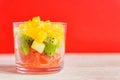 Diet Fresh tasty mix fruit salad in a glass jar on bright red background. Chopped juicy oranges, kiwi and grapefruits Royalty Free Stock Photo