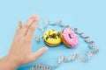 Diet or good health concept. Female hand rejecting unhealthy food like donut or dessert isolated on blue background