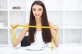 Diet. Happy young smiling woman about to eat one pea holding plate and fork with tape measure. Royalty Free Stock Photo