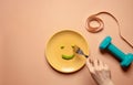 Diet and Health Care Concept. Young Woman Using Fork to Eating Green Soy Bean on Plate. Surrounded by Dumbbell and Soft Tape Royalty Free Stock Photo