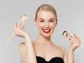 Diet and health concept. Healthy japanese food. Beautiful blonde girl with red lips and manicured nails eating sushi Royalty Free Stock Photo