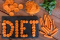 Diet, health, vegetable concept. Different cuts of carrots on a wooden table, word diet on black cutting board Royalty Free Stock Photo