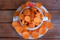 Diet, health, vegetable concept. Round slices of raw carrots in a white bowl on wooden table Royalty Free Stock Photo