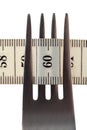 Diet and healthy lifestyle concept. Measuring tape on a fork closeup. Royalty Free Stock Photo