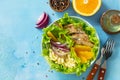 Diet menu. Healthy salad with chicken, egg pancakes, orange, green salad and dressing vinaigrette on a blue stone table.