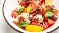 Diet menu. Healthy salad of fresh vegetables with tomatoes, cream cheese balls, prosciutto jamon and basil leaves on a bowl. Flat Royalty Free Stock Photo