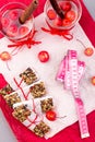 Diet muesli bars with detox apple cinnamon water and measuring tape on red pepper and wooden background. Top view. Flat lay. Royalty Free Stock Photo