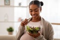 Portrait of happy young pregnant woman eating salad at home Royalty Free Stock Photo