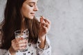 Diet. Nutrition. Smiling girl taking pills with oil Omega-3 cod liver and holding a glass of fresh water in the morning