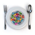 Diet. Pills or vitamins on plate with spoon and fork.