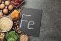 Diet plan for anemia. Different products rich in iron and slate board with Ferrum symbol on grey table, flat lay. Space for text Royalty Free Stock Photo