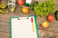 marrow squash, measure tape, blank clipboard, bottle of water, flowers, tomatoes and cucumbers on brown wooden table Royalty Free Stock Photo