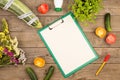 marrow squash, measure tape, blank clipboard, bottle of water, flowers, tomatoes and cucumbers on brown wooden table Royalty Free Stock Photo