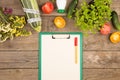 marrow squash, measure tape, blank clipboard, bottle of water, flowers, tomatoes and cucumbers on brown wooden table Royalty Free Stock Photo