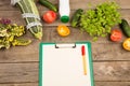 marrow squash, measure tape, blank clipboard, bottle of water, flowers, tomatoes and cucumbers on brown wooden table Royalty Free Stock Photo