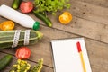 marrow squash, measure tape, blank notepad, bottle of water, flowers, tomatoes and cucumbers on brown wooden table Royalty Free Stock Photo
