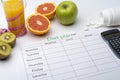 Diet plan on a piece of paper, next to a glass of orange juice. Fresh grapefruit, kiwi and Apple with centimeter on white Royalty Free Stock Photo