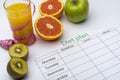 Diet plan on a piece of paper, next to a glass of orange juice. Fresh grapefruit, kiwi and Apple with centimeter on white Royalty Free Stock Photo