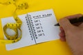 Diet plan text on white notepad with measuring tape on yellow background. Health and diet concept Royalty Free Stock Photo