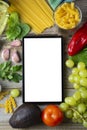 Diet plannig. Set of raw food with tablet on wooden background with gadget screen with copy space. Healthy food concept