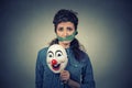 Diet restriction and stress concept. Portrait sad woman with clown mask and measuring tape around her mouth